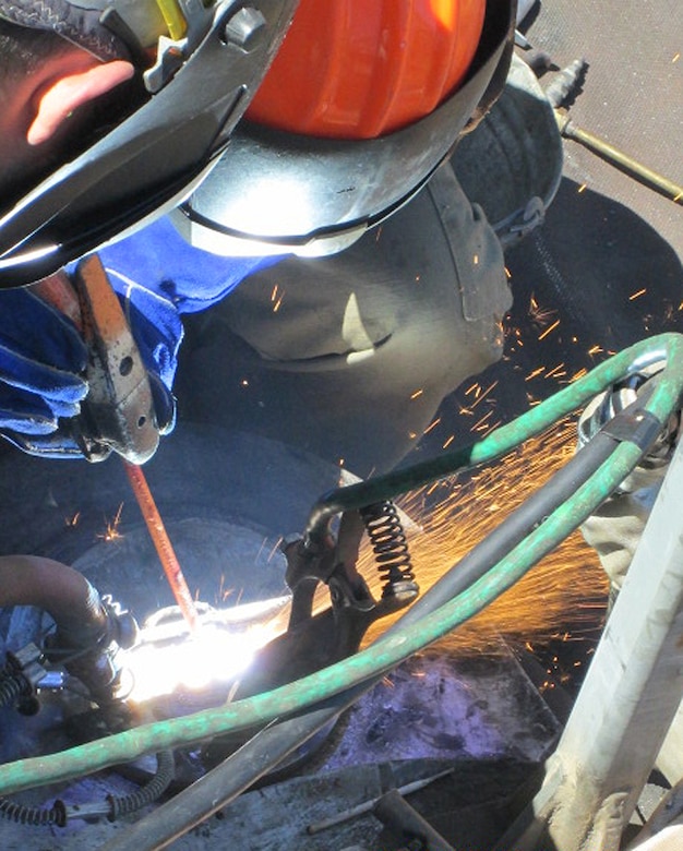 Contractor workers at Little Goose Dam remove components of the cracked gudgeon arm assembly on top of the navigation lock’s south gate leaf. The 50-year-old pins required use of an air-arc cutter to remove them.