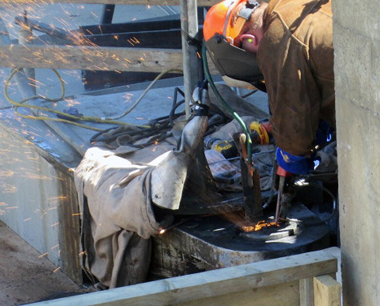 Contractor workers at Little Goose Dam remove components of the cracked gudgeon arm assembly on top of the navigation lock’s south gate leaf. The 50-year-old pins required use of an air-arc cutter to remove them.