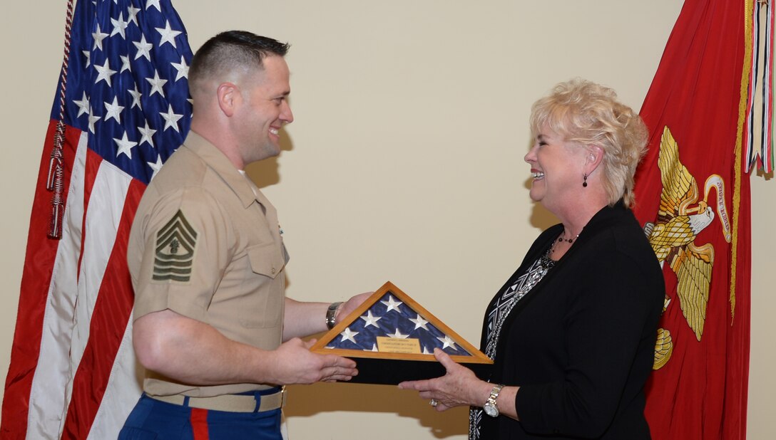 Glenda Hanson receives an American flag from Master Gunnery Sgt. Brent L. Dorrough for her years of dedicated and devoted 30-year, nine-month service during her retirement ceremony, April 3.