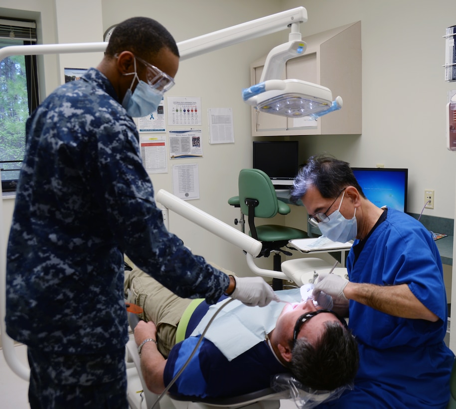 Seaman Aundrea Maddox (left), dental assistant, assists Cmdr. Michael Tai, dentist, with a veteran at the Naval Branch Health Clinic, recently. NBHC Albany now offers dental services to TRICARE eligible retirees and their families on a space available basis at its clinic aboard Marine Corps Logistics Base Albany.