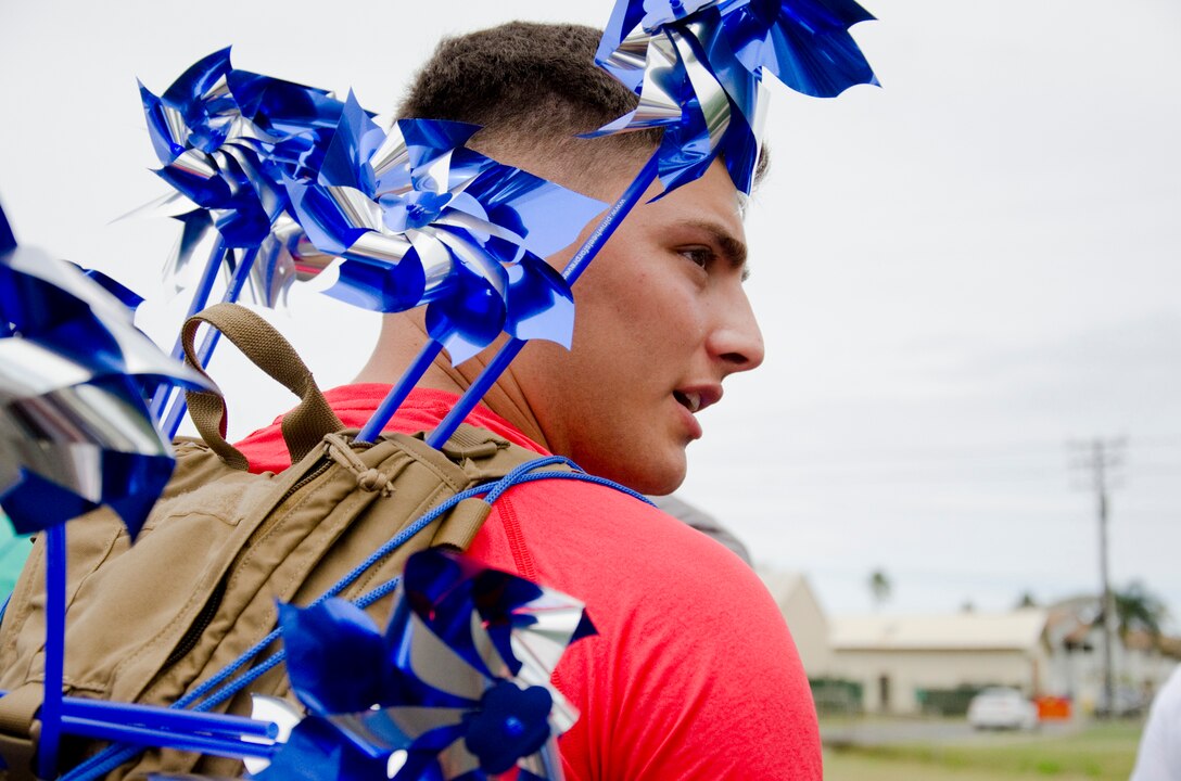 Pfc. Phillip Burford, a motor transport mechanic in the S-4 at 3rd Marine Regiment, carries multiple pinwheels during the Pinwheels for Prevention Walk down Lawrence Road, April 11, 2014. (U.S. Marine Corps photo by Kristen Wong)