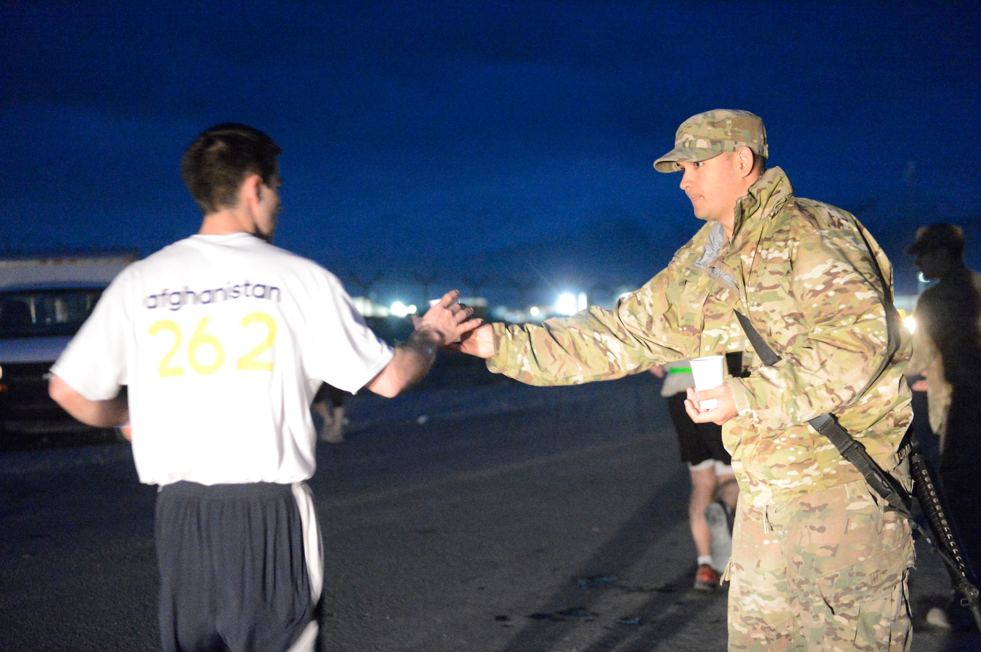 U.S. Air Force Tech. Sgt. Reagancarl O’Connor passes out water to a runner participating in the Boston Marathon Shadow Run-Afghanistan 2014 at Bagram Airfield, Afghanistan, April 18, 2014. Volunteers lined the course, offering water and sports drinks to the runners. O’Connor is deployed from Yokota Air Base, Japan.(U.S. Air Force photo by Senior Master Sgt. Gary J. Rihn/Released)