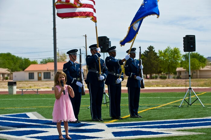 Ella McFadden, daughter of 1st Lt. Michael McFadden, sings the national anthem while the Nellis Air Force Base Honor Guard post the colors for the opening of the 99th Logistics Readiness Squadron Life of a Warrior Challenge April 11, 2014, at Nellis Air Force Base, Nev. A total of 19 teams participated in this challenge. (U.S. Air Force photo by Airman 1st Class Jake Carter)