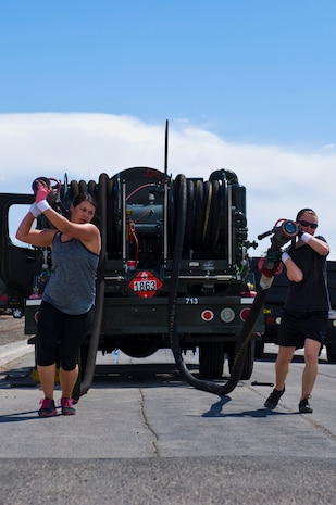 (left)Senior Airman Justine Karavites, U.S. Air Force Warfare Center paralegal, and Capt. Lindsay Cronin, USAFWC assistant staff judge advocate, move fuel hoses during the 99th Logistics Readiness Squadron Life of a Warrior Challenge April 11, 2014, at Nellis Air Force Base, Nev. A total of 19 teams participated in the 99th LRS Life of a Warrior Challenge. (U.S. Air Force photo by Senior Airman Christopher Tam)
