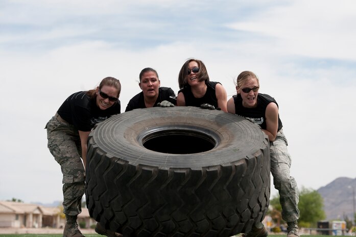 Team "Command Section Two" lift a tire during the 99th Logistics Readiness Squadron Life of a Warrior Challenge April 11, 2014, at Nellis Air Force Base, Nev. Lifting a tire across the football field was one of the stations at the Warrior Challenge competition. (U.S. Air Force photo by Senior Airman Christopher Tam)