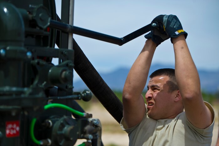 Staff Sgt. Larry Torres, 99th Logistics Readiness Squadron NCO in charge of team three vehicle flight, cranks in a fuel hose during the 99th LRS Life of a Warrior Challenge April 11, 2014, at Nellis Air Force Base, Nev.  Nine different stations tested teams physically and mentally endurance. (U.S. Air Force photo by Senior Airman Christopher Tam)