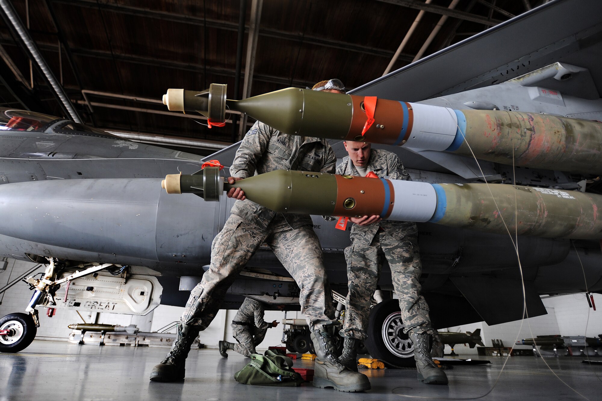 U.S. Air Force Senior Airman Patrick Manor and Staff Sgt. Randy Therriault, both 20th Maintenance Group weapons load crew members, work together to quickly load munitions onto an F-16CJ Fighting Falcon during a load crew of the year competition, April 18, 2014, Shaw Air Force Base, S.C. The 20th Fighter Wing weapons standardization unit held the annual competition which brings together weapons load crew members from all three fighter squadrons at Shaw to compete against each other. The competition showcases Airmen’s skills and job knowledge while also building camaraderie amongst the units. (U.S. Air Force photo by Staff Sgt. Kenny Holston/Released)