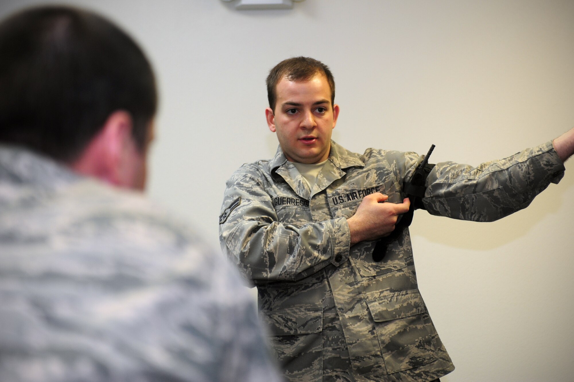 Airman 1st Class Justin Gueresso, self-aid and buddy care instructor, demonstrates how to properly self-apply a tourniquet during a hands on SABC class at Fairchild Air Force Base, Wash, April 17, 2014. SABC encompasses basic life support and limb-saving techniques to help wounded or injured personnel survive in medical emergencies until medical help is available. (U.S. Air Force photo by Senior Airman Taylor Curry/Released) 