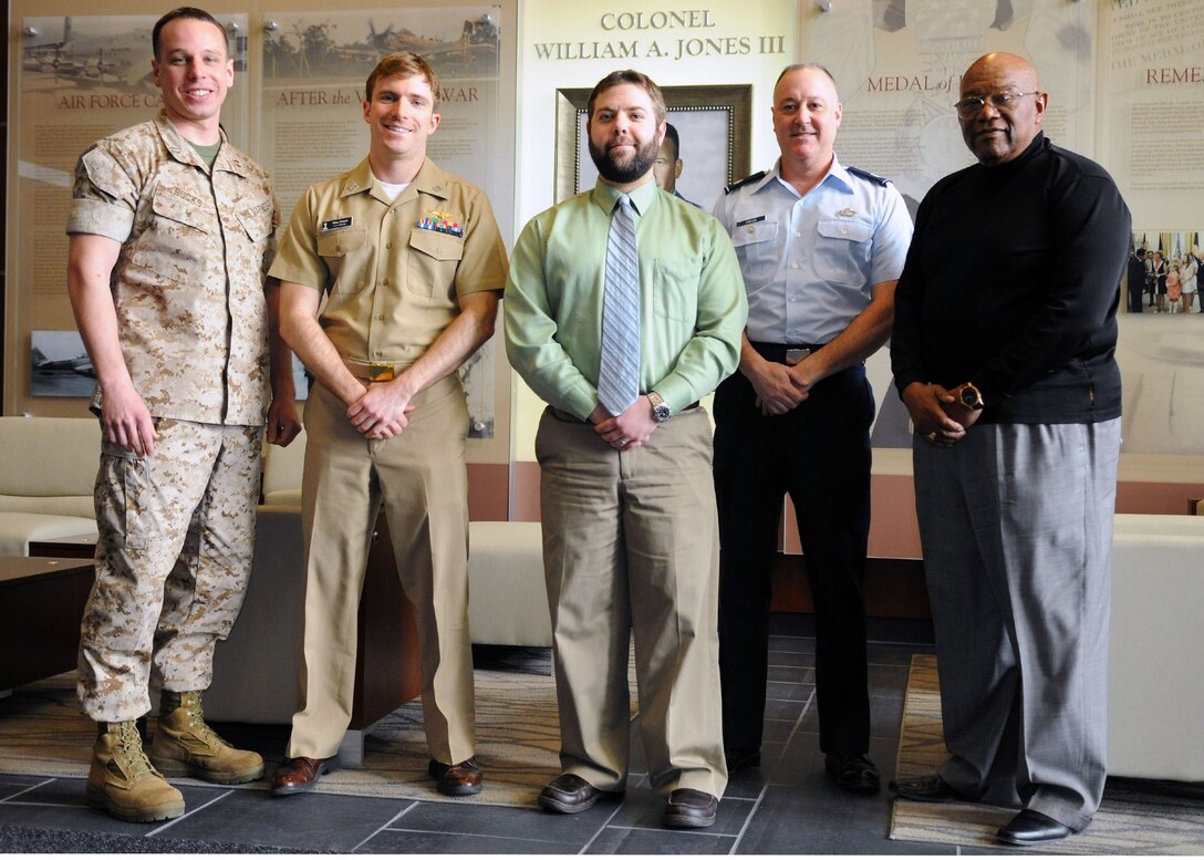 The Armed Forces Entertainment team poses for a photo at the William A. Jones III Building lobby on Joint Base Andrews, Md., March 26, 2014. From left to right: Marine Capt. Marc Bucks, Navy Lt. Max Mayer, Brian Burke, Lt. Col. John Ponton, and Elmo Gladden. (U.S. Air Force photo by Aimee Fujikawa)