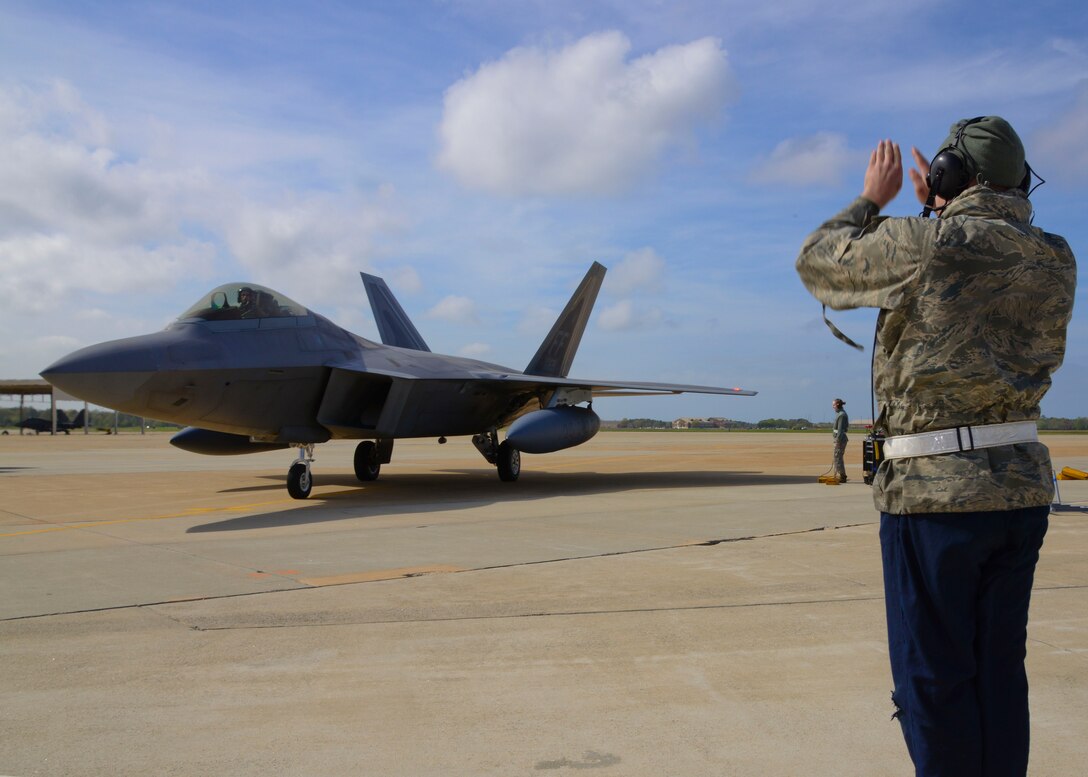 A 94th Fighter Squadron crew chief marshals in a F-22 Raptor at Langley Air Force Base, Va., April 17, 2014. The 94th FS deployed for nearly four-months to Kadena Air Base, Japan, to demonstrate the continued U.S. commitment to help maintain peace throughout the Western Pacific. (U.S. Air Force photo by Staff Sgt. Antoinette Gibson/Released)