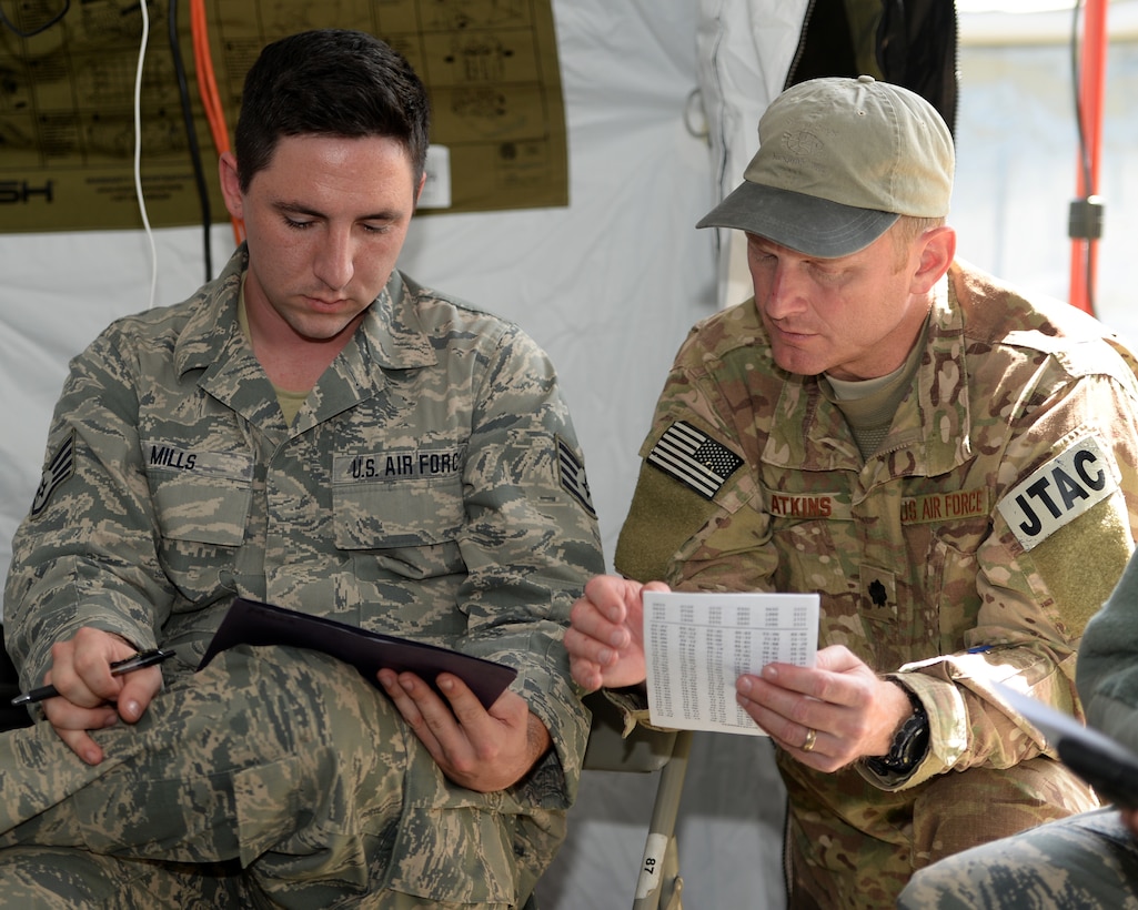 Staff Sgt. Joseph Mills, a radio technician with the 147th Air Support Operations Squadron, 147th Reconnaissance Wing, based at Ellington Field Joint Reserve Base in Houston, Texas, works with Lt. Col. Nigel Atkins, the squadron commander, on encoding/decoding training during a field training exercise April 3, 2014, at Camp Swift in Bastrop, Texas. The support personnel participated in the annual exercise to test the requirements necessitated by being members of an ASOS unit.