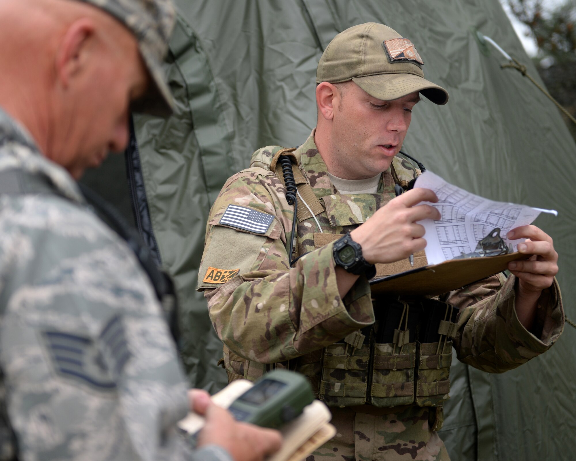 A vehicle maintenance airman with the 147th Air Support Operations Squadron, 147th Reconnaissance Wing, based at Ellington Field Joint Reserve Base in Houston, Texas, reads off waypoints to another airman from the squadron during a field training exercise April 3, 2014, at Camp Swift in Bastrop, Texas. The support personnel participated in the annual exercise to test the requirements necessitated by being members of an ASOS unit.