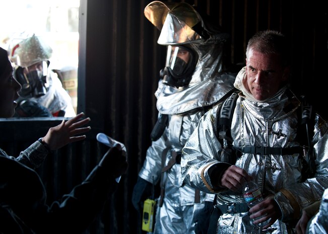 Maj. Gen. Jay Silveria, U.S. Air Force Warfare Center commander, receives a briefing from Tech. Sgt. Vanessa Wyatt, 99th Civil Engineer Squadron NCOIC of training fire emergency services, on how to suppress a structural fire at the structural trainer April 17, 2014, at Nellis Air Force Base, Nev. 99th CES firefighters train to respond to both aircraft and structural fires. (U.S. Air Force photo by Airman 1st Class Thomas Spangler)