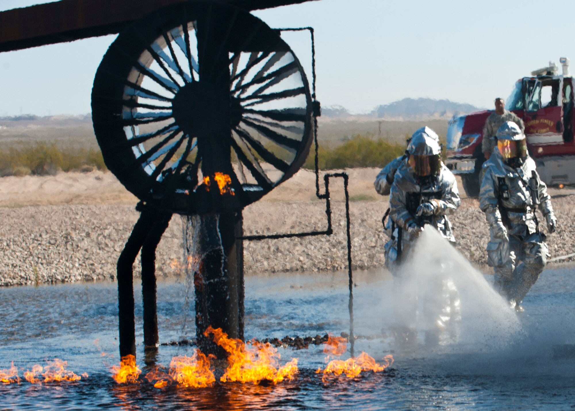 Maj. Gen. Jay Silveria, U.S. Air Force Warfare Center commander, suppresses a fire during a firefighting exercise at the Aircraft Burn Trainer April 17, 2014, at Nellis Air Force Base, Nev. Silveria was participating in a fire suppression exercise with the 99th Civil Engineer Squadron. The 99th CES firefighters train on the aircraft burn trainer for potential real-world aircraft fires. (U.S. Air Force photo by Airman 1st Class Thomas Spangler)