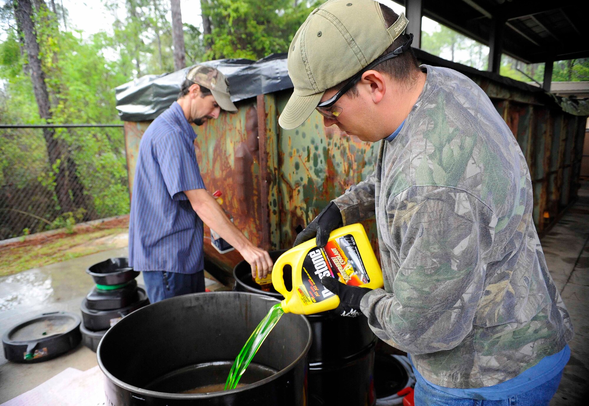 Staff Sgt. Josiah Chakerian, 1st Special Operations Maintenance Operations Squadron technical analyst, and Marcus Wilson, environmental company waste manager, pour hazardous material into gel drums at Hurlburt Field, Fla., April 18, 2014. Hazardous liquids can be recycled or burned for energy. (U.S. Air Force photo/Airman 1st Class Andrea Posey)