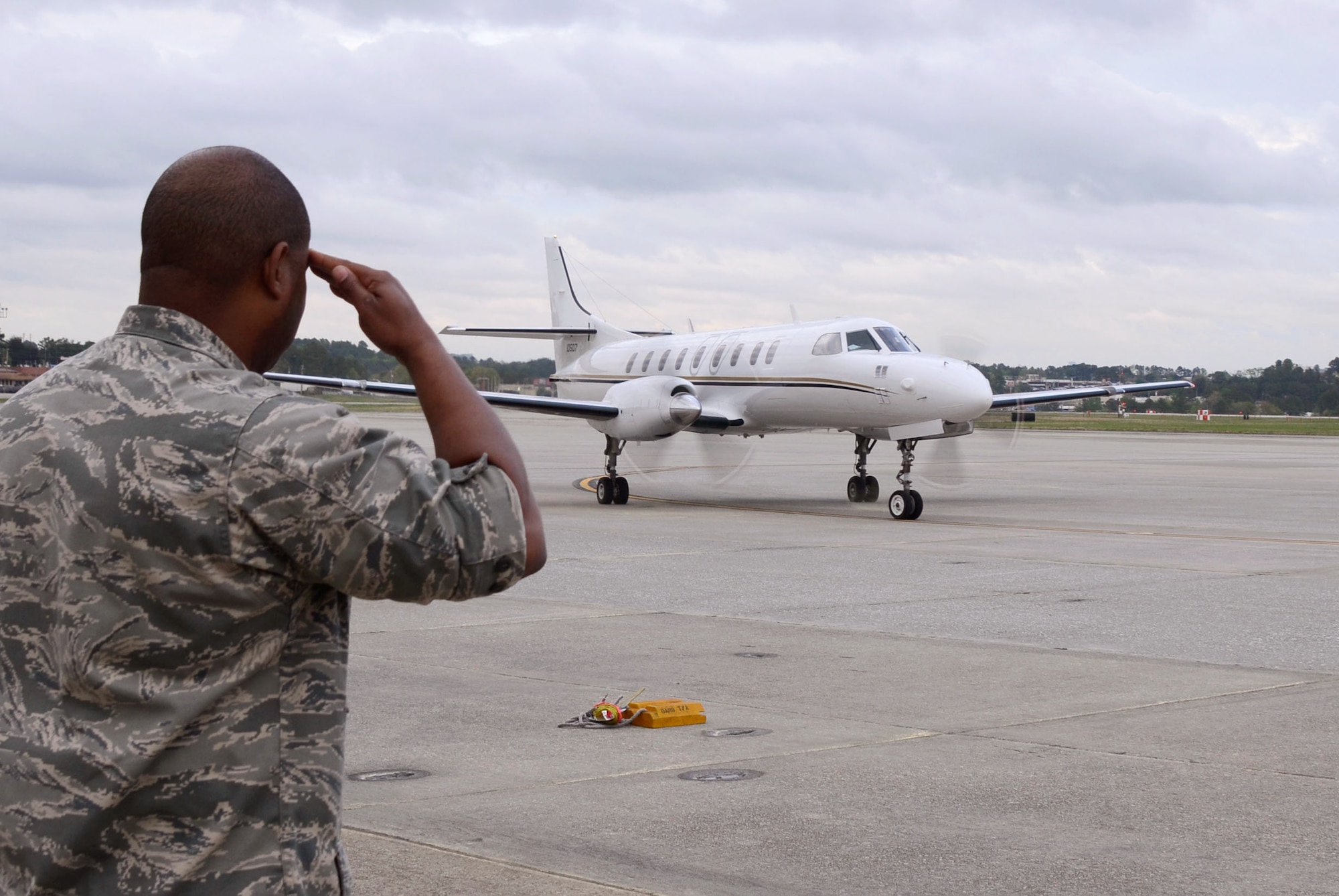 Maj. Quincy D. Hudson, 94th Airlift Wing protocol officer, renders a salute as the C-26 aircraft with Maj. Gen. Dwyer L. Dennis, Program Executive Officer for Fighters and Bombers, Air Force Life Cycle Management Center (AFLCMC), Air Force Materiel Command, Wright-Patterson Air Force Base, Ohio lands at Dobbins Air Reserve Base, Ga. April 14. Dennis and accompanying Wing Commanders will be on Dobbins for an offsite conference. Dennis and his team are welcomed by Hudson and Col. Marshall S. Irvin Jr., 94th Mission Support Group, commander. (U.S. Air Force photo/Don Peek)