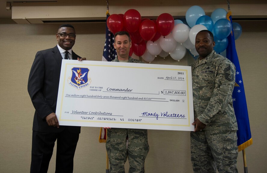 Victor Johnson, 23d Force Support Squadron career readiness specialist, left, U.S. Air Force Col. Chad Franks, middle, 23d Wing commander, and Chief Master Sgt. Gregory Brown, 23d Fighter Group chief enlisted manager, hold a symbolic check during a volunteer recognition ceremony at Moody Air Force Base, Ga., April 17, 2014. The check symbolized more than $1.8 million volunteers saved the base and community through manhours. (U.S. Air Force photo by Senior Airman Jarrod Grammel/Released) 
