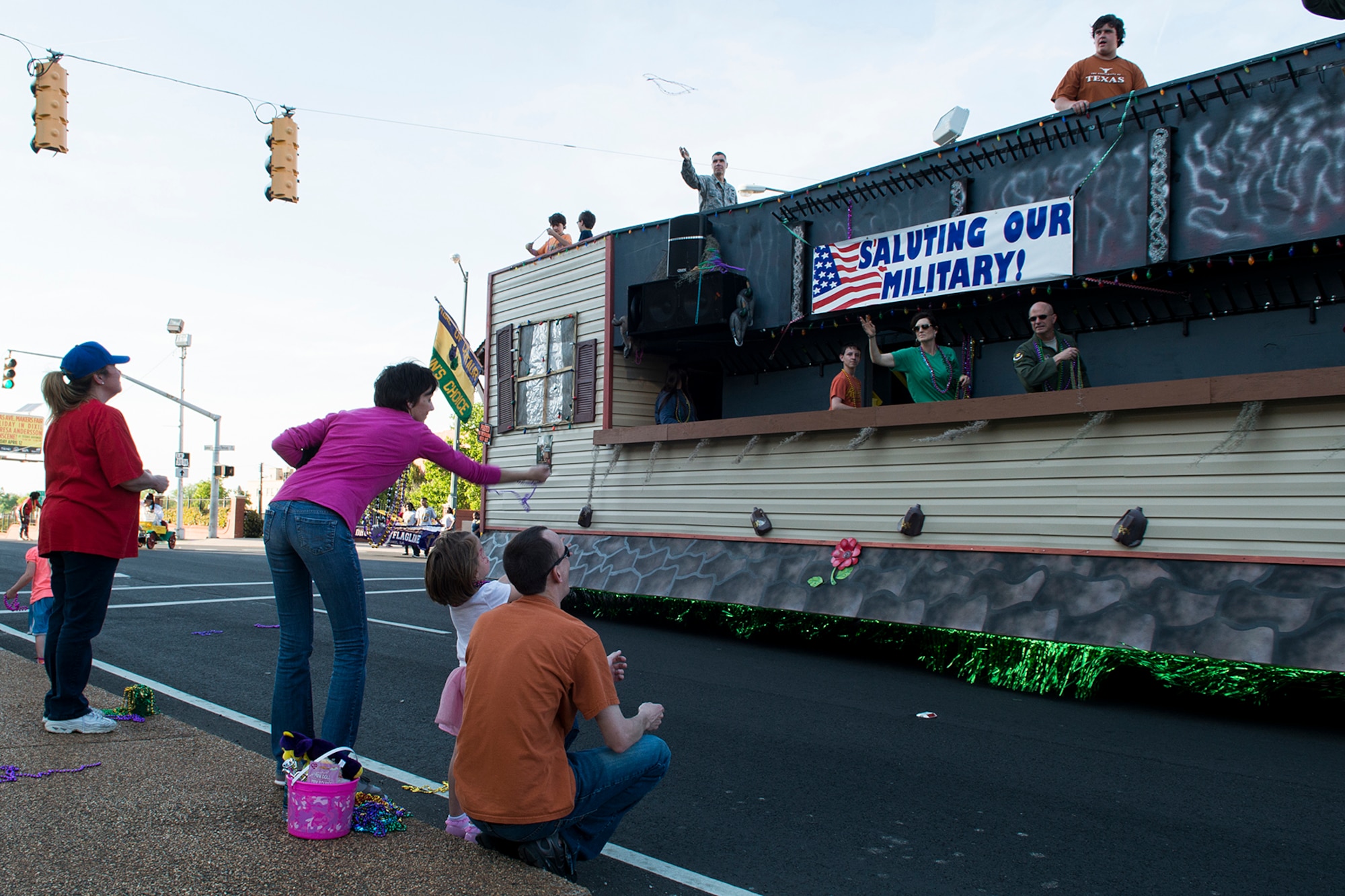People along the Holiday in Dixie parade route catch beads thrown from a float, April 12, 2014, Shreveport, La. 307th Bomb Wing Airmen and their family members were invited to participate in the parade, which is an annual spring event in Shreveport. (U.S. Air Force photo by Master Sgt. Greg Steele/Released)