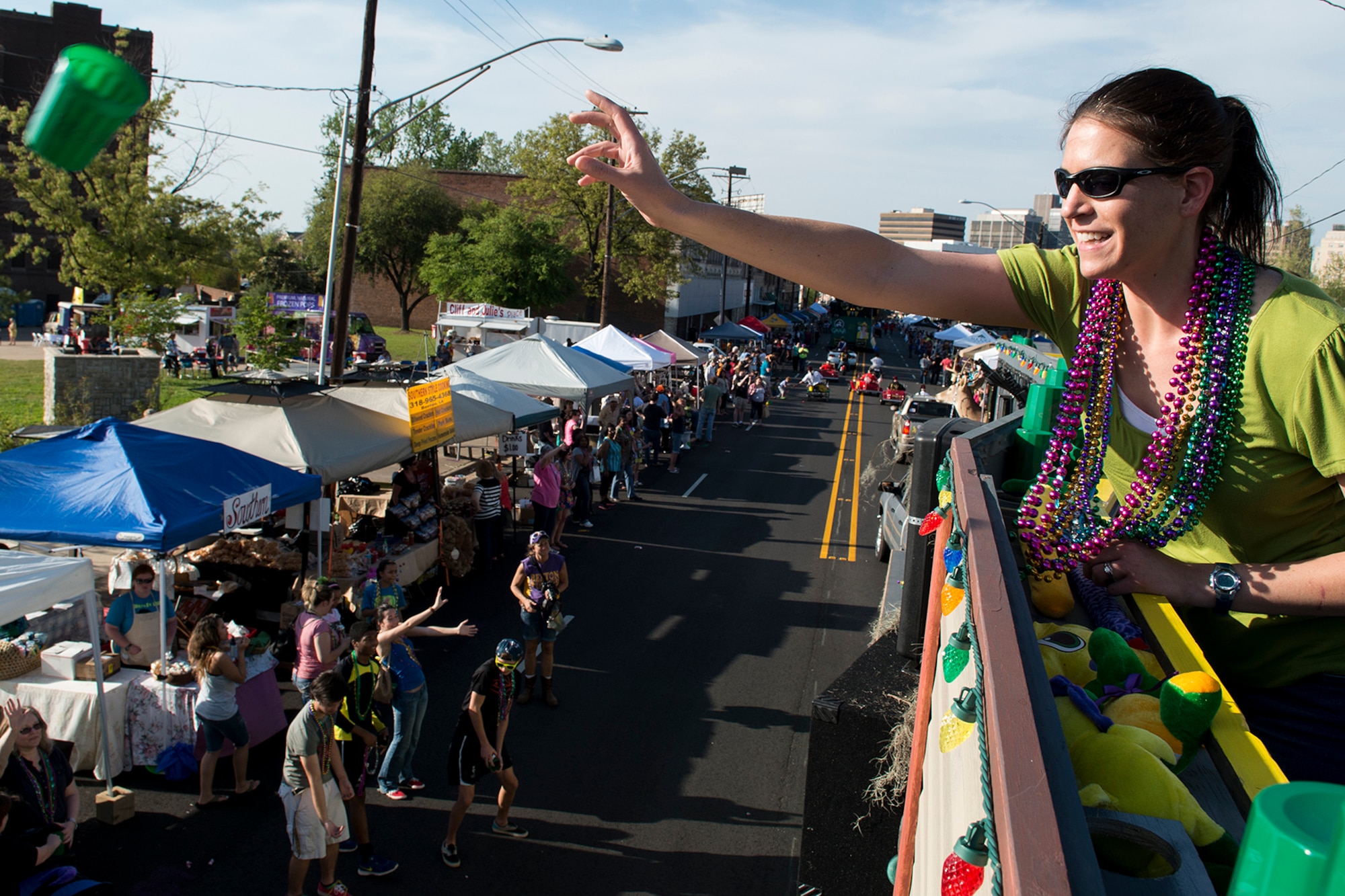 Jenny Rose, wife of U.S. Air Force Col. Kenneth Rose, 307th Maintenance Squadron commander, throws a souvenir cup to people along the Holiday in Dixie parade route, April 12, 2014, Shreveport, La. 307th Bomb Wing Airmen and their family members manned the "Salute to Military" float during the parade. (U.S. Air Force photo by Master Sgt. Greg Steele/Released)