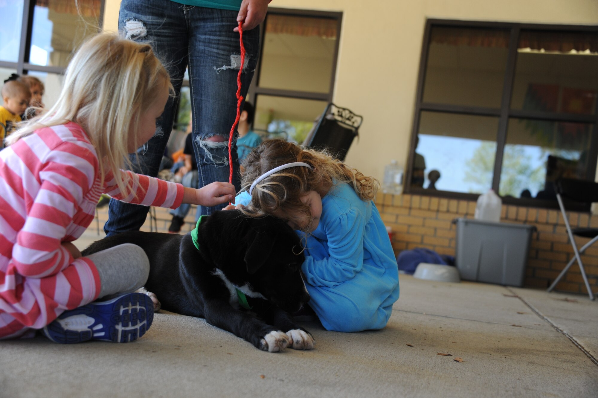 Smoke embraces hugs from children at the Maxwell Child Development Center April 16, 2014. Three adoptable dogs visited the center in celebration of Month of the Military Child. (U.S. Air Force photo by Staff Sgt. Natasha Stannard)