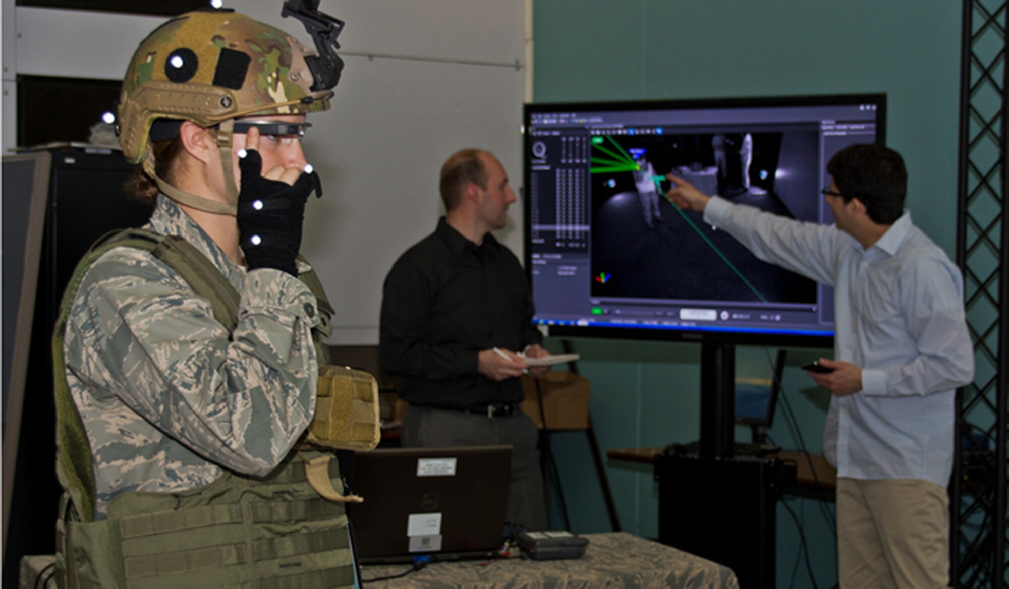 Dr. Gregory Burnett, middle, and Andres Calvo, right, analyze a graphic representation of movement trackers, as 2nd Lt. Krystin Shanklin tests Google Glass at Wright-Patterson Air Force Base, Ohio. Burnett is the chief engineer of the Battlefield Air Targeting, Man-Aided Knowledge, or BATMA(N) group, an advanced technology demonstration and research program at the 711 Human Performance Wing at the Air Force Research Laboratory. The team investigates emerging technologies, such as Google Glass' transparent, heads-up display, for possible military application. Calvo is a software developer and civilian contractor with the Wing. (U.S. Air Force photo/ Richard Eldridge) 