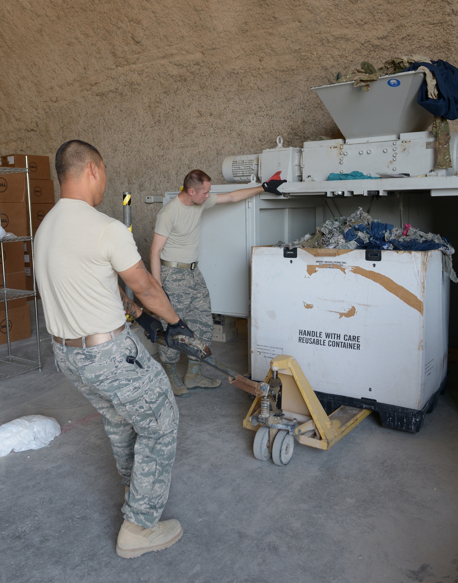 Staff Sgt. Vianney Hocog and Tech. Sgt. Patrick Keenan move a box of shredded military uniforms at Al Udeid Air Base, Qatar, Apr. 17, 2014. The 379th Air Expeditionary Wing Force Protection shop collects and shreds unserviceable military uniforms weekly to prevent operation security violations and ensure adversaries do not have an opportunity to impersonate U.S. military members for an attack. Hocog the 379th AEW Force Protection NCO in charge, deployed from Tyndall Air Force Base, Fla., and a Rota, Mariana Islands, native. Keenan the 379th AEW Operations Security program manager here on a one year tour and an Ischua, N.Y., native. (U.S. Air Force photo/Senior Airman Hannah Landeros)
