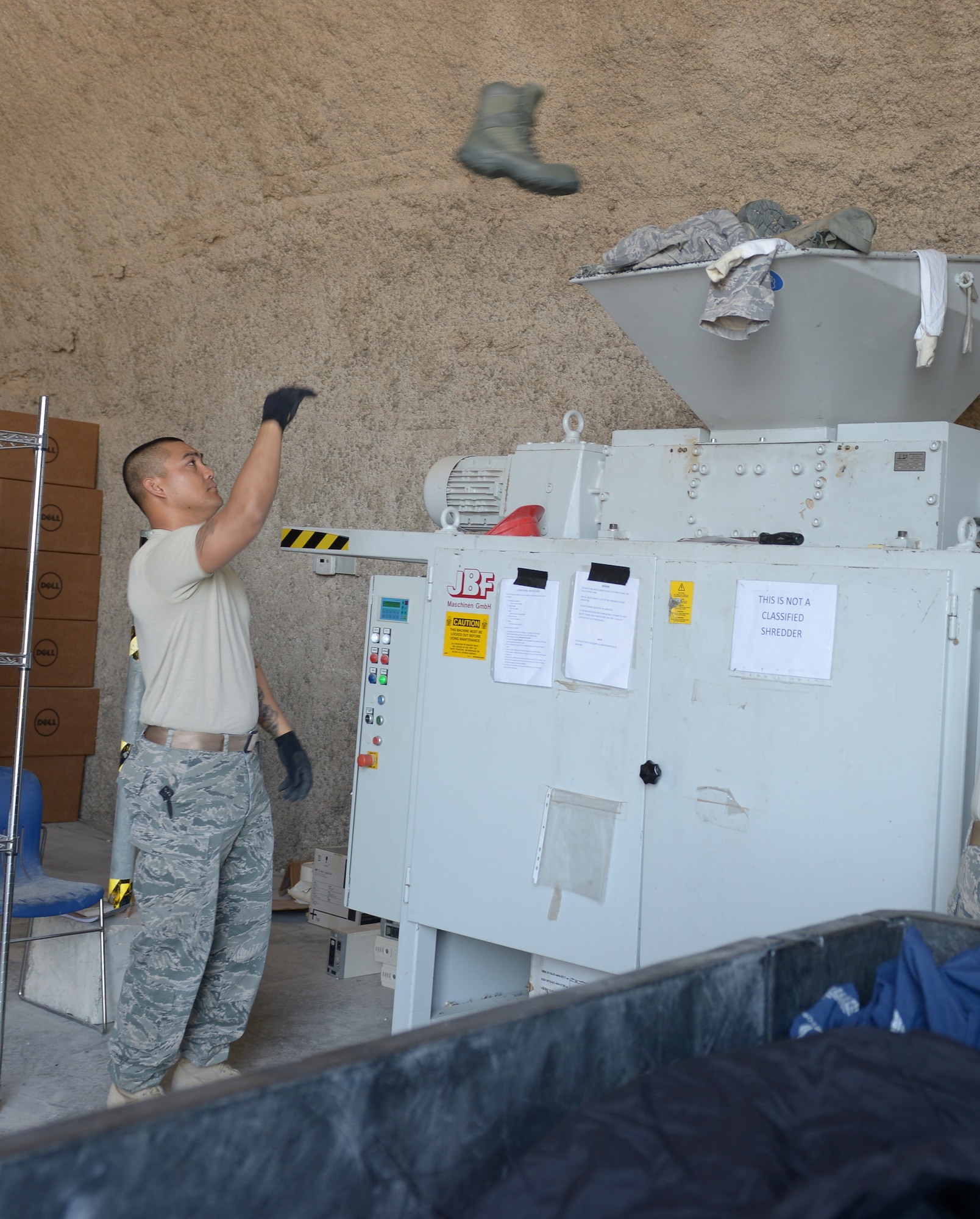 Staff Sgt. Vianney Hocog tosses a boot into the shredder at Al Udeid Air Base, Qatar, Apr. 17, 2014. The 379th Air Expeditionary Wing Force Protection shop collects and shreds unserviceable military uniforms weekly to prevent operation security violations and ensure adversaries do not have an opportunity to impersonate U.S. military members for an attack. Hocog the 379th AEW Force Protection NCO in charge, deployed from Tyndall Air Force Base, Fla., and a Rota, Mariana Islands, native. (U.S. Air Force photo/Senior Airman Hannah Landeros)