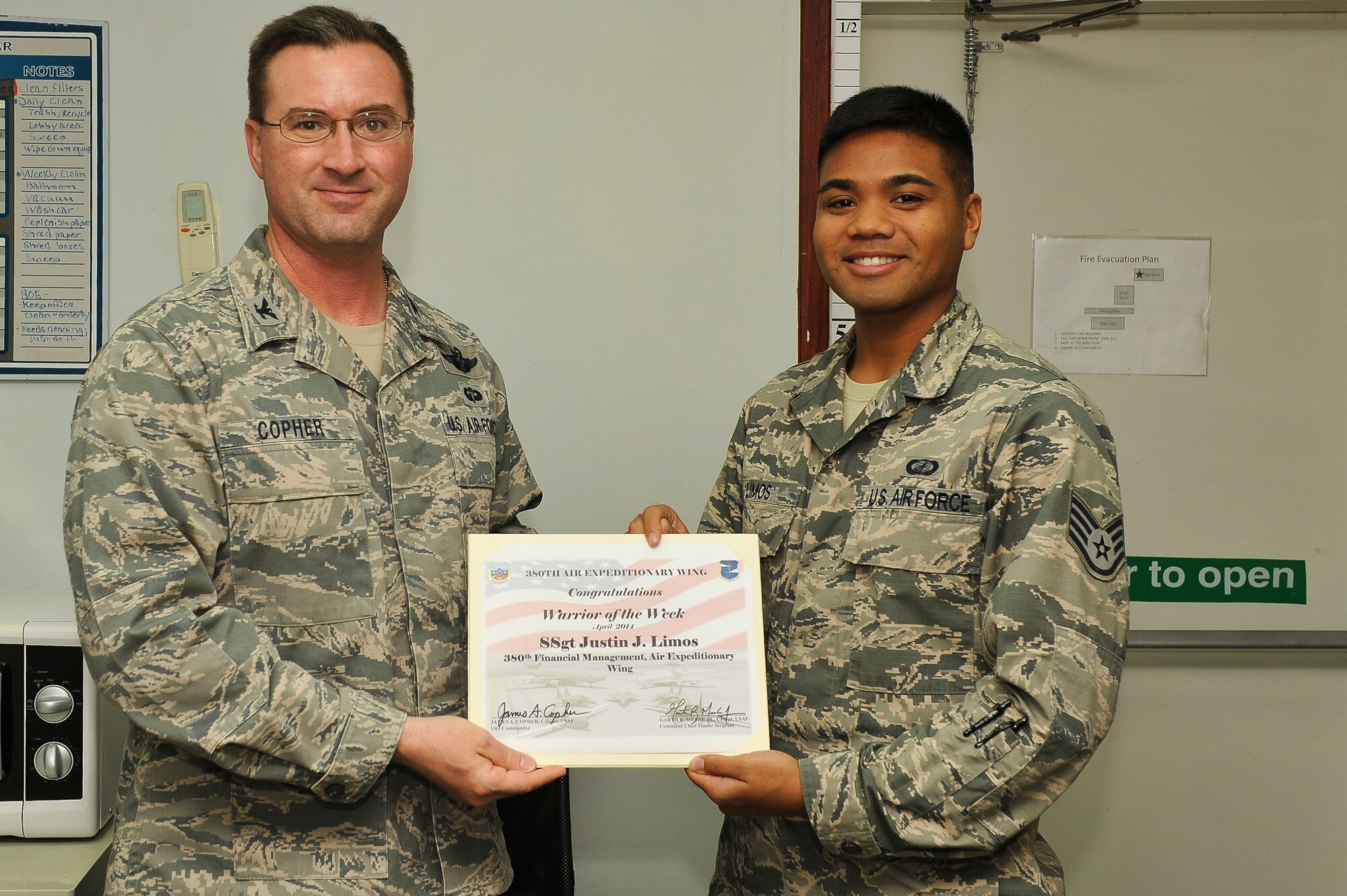 Air Force Col. James Copher, 380th Air Expeditionary Wing vice commander, presents Air Force Staff Sgt. Justin Limos, 380th Expeditionary Security Forces Squadron unit deployment manager, a warrior of the week certificate at an undisclosed location in Southwest Asia, April 9, 2014. Smith is a native of Dixon, Calif., has a shetland sheepdog named Russell and is deployed from Joint Base Langley-Eustis, Va. (U.S. Air Force photo by Tech. Sgt. Russ Scalf/Released)