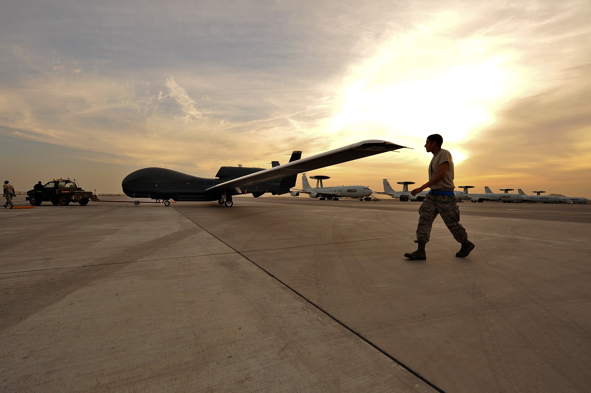 Airmen from the 380th Expeditionary Aircraft Maintenance Squadron tow an RQ-4 Global Hawk April 15, 2014, at an undisclosed location in Southwest Asia. The Global Hawk is an unmanned aircraft that provides intelligence, surveillance, reconnaissance and communications capabilities over Southwest Asia. (U.S. Air Force photo by Tech. Sgt. Russ Scalf/Released)