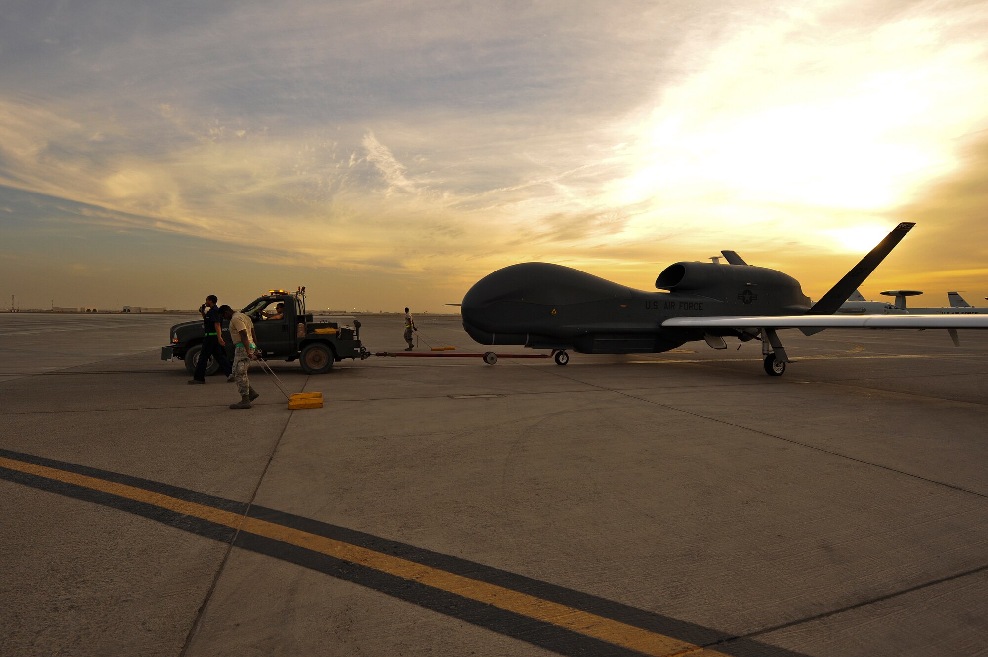 Airmen from the 380th Expeditionary Aircraft Maintenance Squadron tow an RQ-4 Global Hawk April 15, 2014, at an undisclosed location in Southwest Asia. The Global Hawk is an unmanned aircraft that provides intelligence, surveillance, reconnaissance and communications capabilities over Southwest Asia.(U.S. Air Force photo by Tech. Sgt. Russ Scalf/Released)