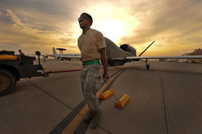 Senior Airman Arrelius Oliver, a 380th Expeditionary Aircraft Maintenance Squadron assistant dedicated crew chief, drags the chocks for an RQ-4 Global Hawk April 15, 2014, at an undisclosed location in Southwest Asia. Arrelius, deployed from Beale Air Force Base, Calif., was part of a crew preparing the aircraft for a mission that evening.  (U.S. Air Force photo by Tech. Sgt. Russ Scalf/Released)