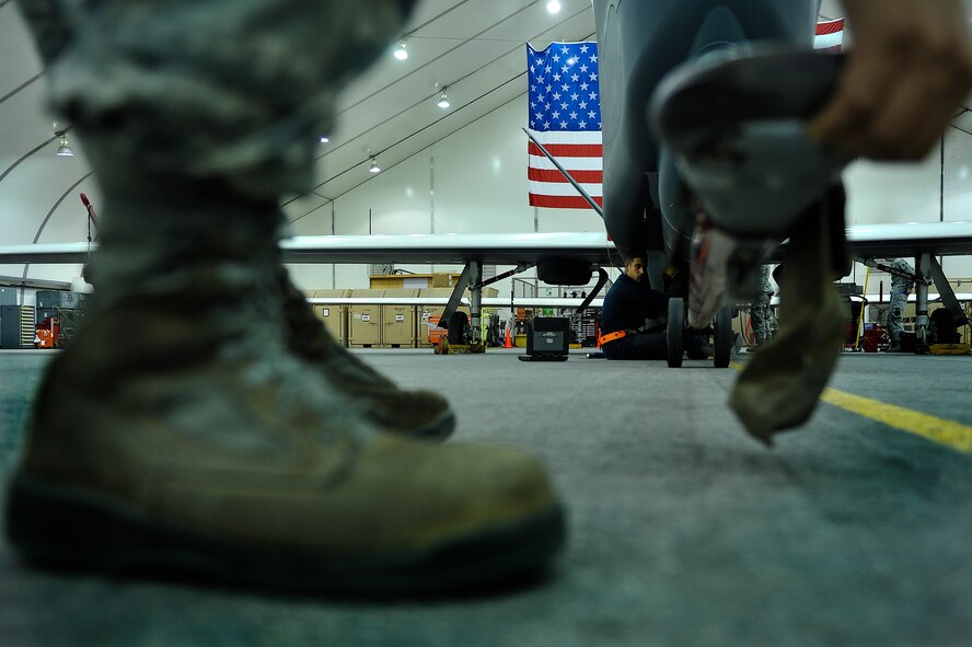 Senior Airman Blaine Aponte and Staff Sgt. Juan Lopez, members of the 380th Expeditionary Aircraft Maintenance Squadron, remove a tow bar from an RQ-4 Global Hawk prior to conducting maintenance operations April 15, 2014, at an undisclosed location in Southwest Asia. The Global Hawk provides intelligence, surveillance, reconnaissance and communications capabilities over Southwest Asia.  (U.S. Air Force photo by Tech. Sgt. Russ Scalf/Released)