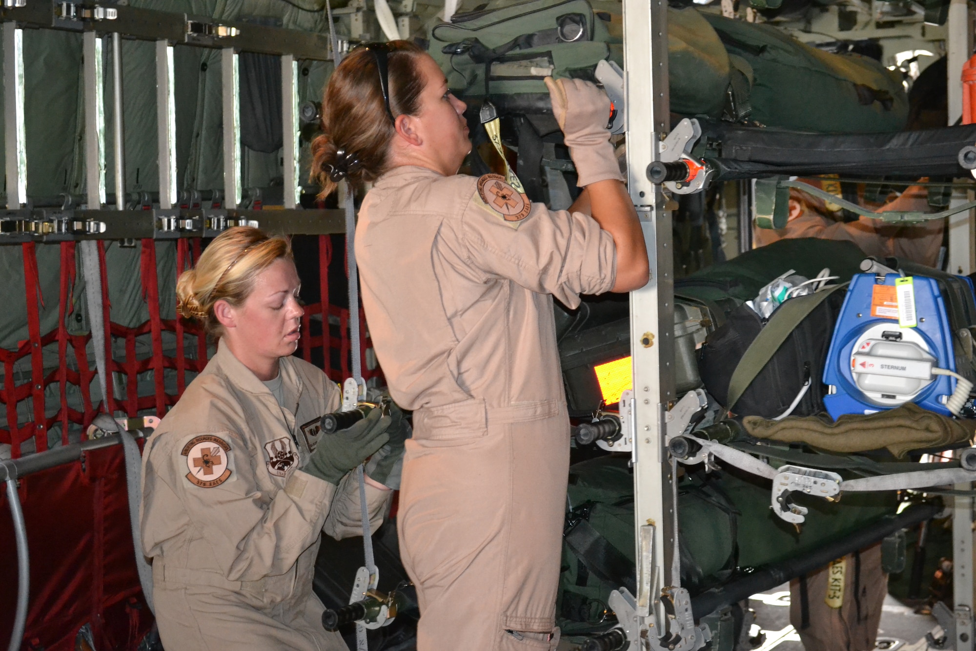 Staff Sgt. Molly Farrand and Senior Airman Deonda De Leon, medical technicians with the 379th Expeditionary Aeromedical Evacuation Squadron, secure the litters as they load them on the C-130 Hercules prior to an AE mission in support of Operation Enduring Freedom, April 16, 2014, Al Udeid Air Base, Qatar.  A crew of two nurses and three medical technicians work as a choreographed team as they configure, load, and inspect all emergency equipment litters and medical supplies on the aircraft to ensure function and preparation for any and all types of medical emergencies, as well as safety for all crew and patient on board.  Farrand is deployed from the Wyoming Air National Guard and a Fort Collins, Colo. native.  De Leon is deployed from Ramstein Air Base, Germany and a native of Vanceburg, Ky.  (U.S. Air Force photo by Maj. Nicole David) 