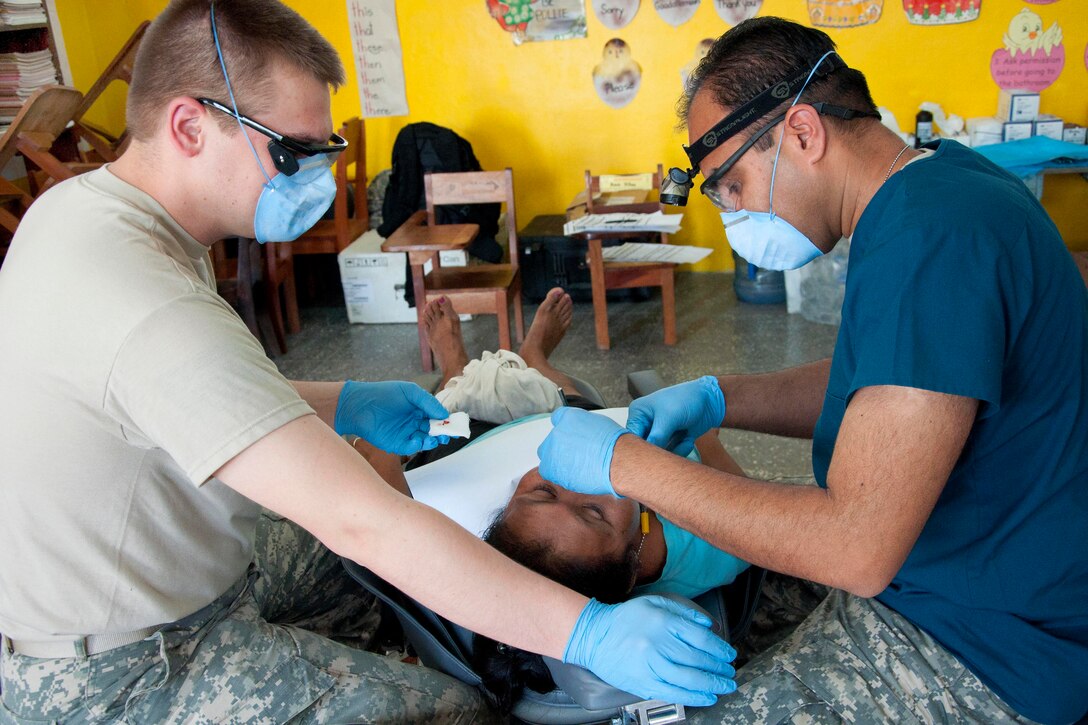 U.S. Army Spc. Steven Dixon, left, and U.S. Army Capt. Harjind Sidhu examine a patient's teeth in Progresso, Belize, April 11, 2014. Dixon is a dental technician and Sidhu is a dentist.