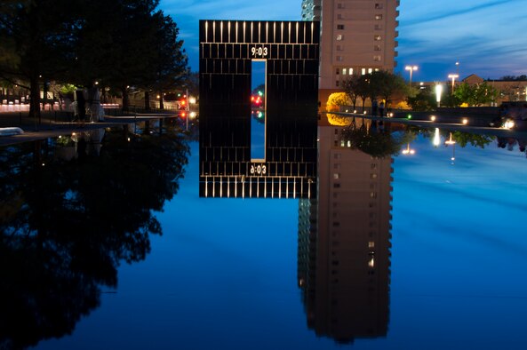 The sun sets on the Oklahoma City Memorial site.  One of the Gates of Time lights up to reveal the moment just after the Alfred P. Murrah Federal Building was bombed.  The site of the Reflecting Pool leading west toward this gate was once N.W. 5th St., with the Murrah Building just to the left.  (U.S. Air Force photo/Senior Airman Mark Hybers)