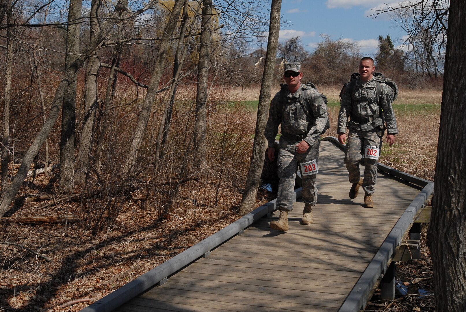 Wearing a race bib with the number 203 on it, Staff Sgt. Jarred Turner, truck driver, 2123rd Transportation Company, Kentucky Army National Guard, walks along the historic Minute Man National Park during a 26.2-mile ruck march to honor fallen service members and raise money to assist their surviving family members, April 19, 2014.