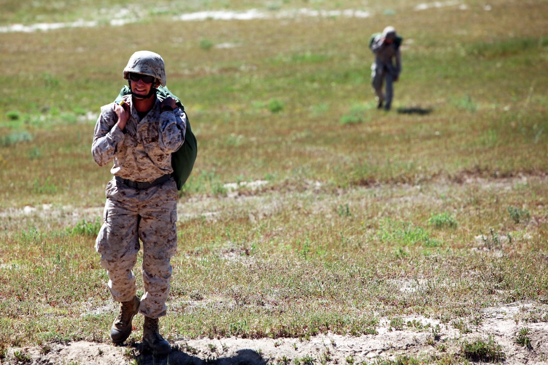 Cpl. Joseph Marshall, parachute rigger air delivery specialist, 1st Radio Battalion, I Marine Expeditionary Force, carries his parachute after completing a jump out the back of a C-130 as a guest during an aerial resupply training procedure aboard Camp Pendleton, Calif., April 11, 2014. Air delivery specialists must jump out of aircraft to meet the quarterly requirement for their job. This training allows air delivery Marines to practice the capabilities that allow supplies to reach Marines in combat or personnel in a natural disaster when a safe ground route is unavailable.