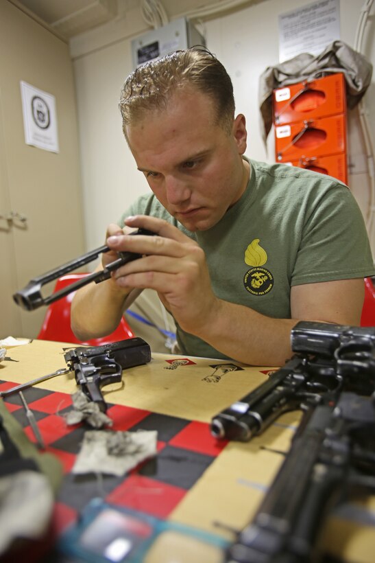 Corporal Michael Yodice inspects and cleans M9 service pistols aboard amphibious transport dock ship USS Anchorage (LPD 23). Yodice is from Butler, N.J., and the sole Marine Corps armorer aboard the ship. As a small arms repair technician with 1st Maintenance Battalion, 1st Marine Logistics Group, he was responsible for making sure the different weapons systems worked for the nearly 200 Marines and sailors with his current