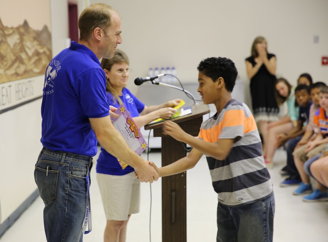 Paul Gattuso, principal, Condor Elementary School, awards Kendrick Hudson, 12, with a People Respecting Others (PRO) award during a ceremony at the school, April 11, 2014. “Our students here face unique challenges with parents sometimes being deployed,” Gattuso said. “On top of everything they may be going through at home, it shows true resiliency and adaptability on their part to earn these achievements.” (Official Marine Corps Photo By Lance Cpl. Kasey Peacock/Released)
