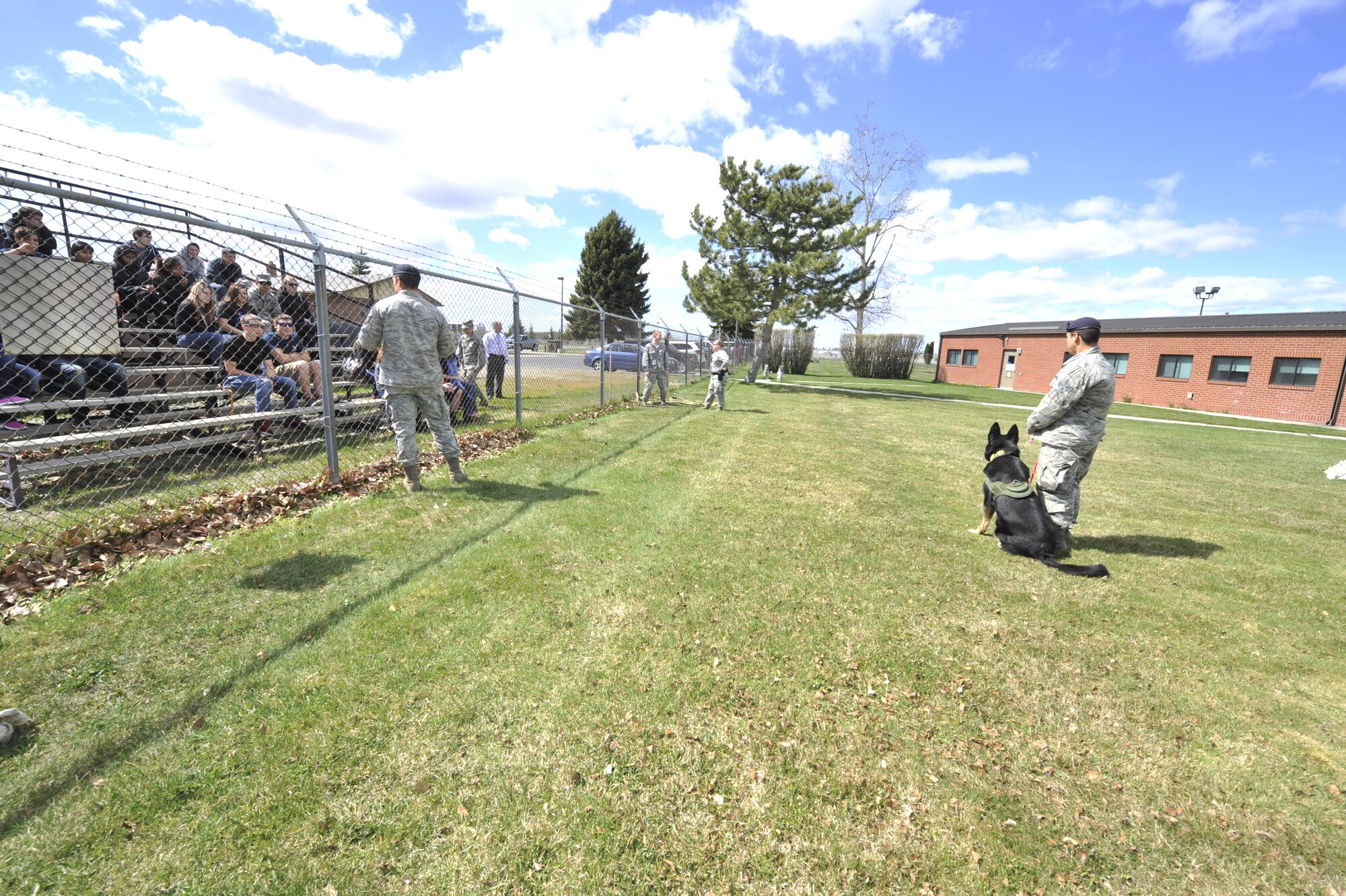 Members of the 92nd Security Forces Squadron military working dog team, provide a training demonstration for members of the Delayed Enlistment Program during a base tour at Fairchild Air Force Base, Wash., April 18, 2014. During the tour, the future military members visited the base gym, dormitory facilities, education center and more to better understand the lifestyle. (U.S. Air Force photo by Senior Airman Mary O'Dell/Released)