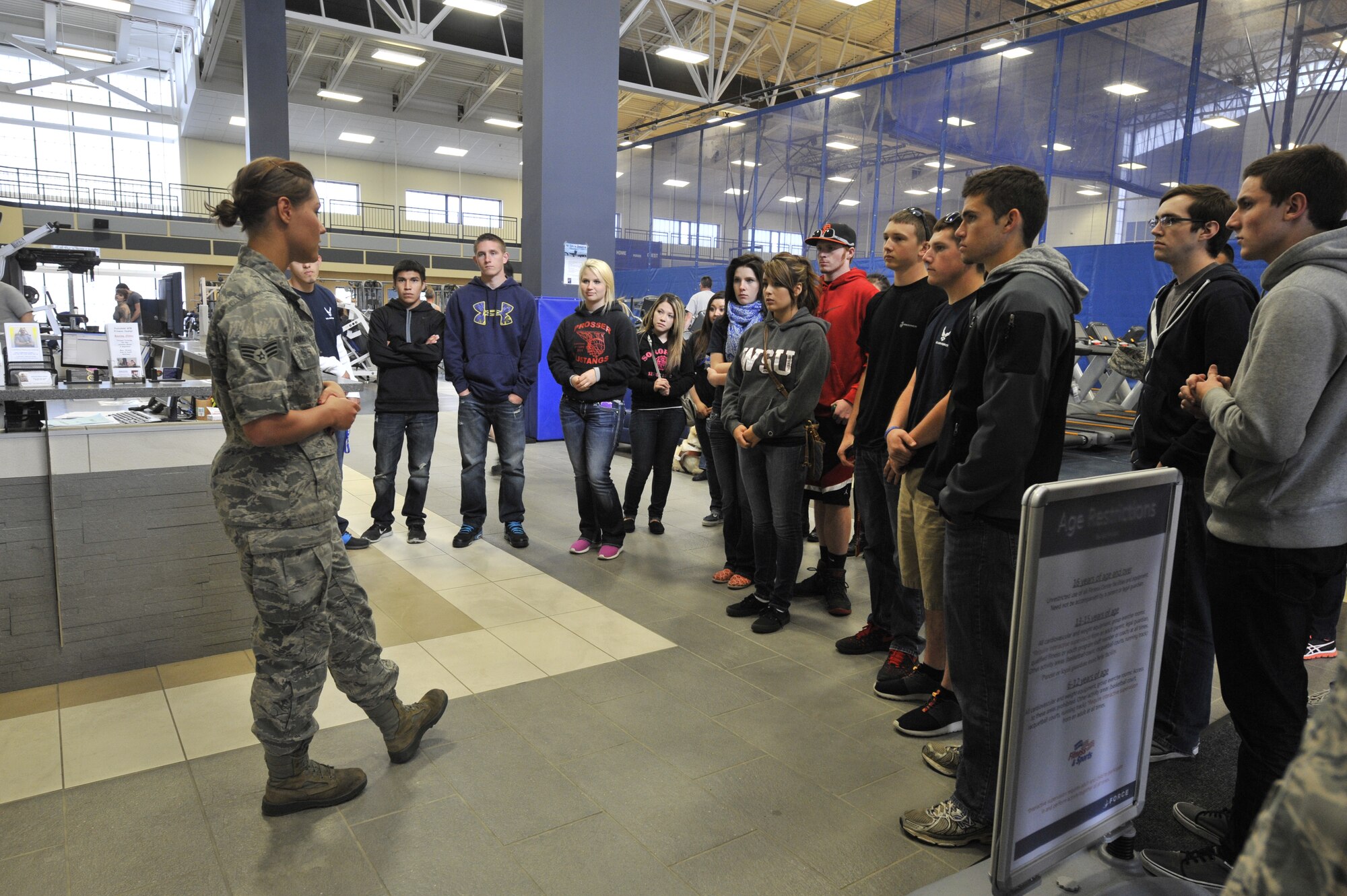 Senior Airman Guinevere Running Wolf speaks to members in the Delayed Entry Program at the gym during a base tour at Fairchild Air Force Base, Wash., April 18, 2014. Running Wolf spoke about the different programs the fitness center and health and wellness center offer to military members and their families. Running Wolf is a 92nd Force Support Squadron NCO in-charge of fitness assessments. (U.S. Air Force photo by Senior Airman Mary O'Dell/Released)