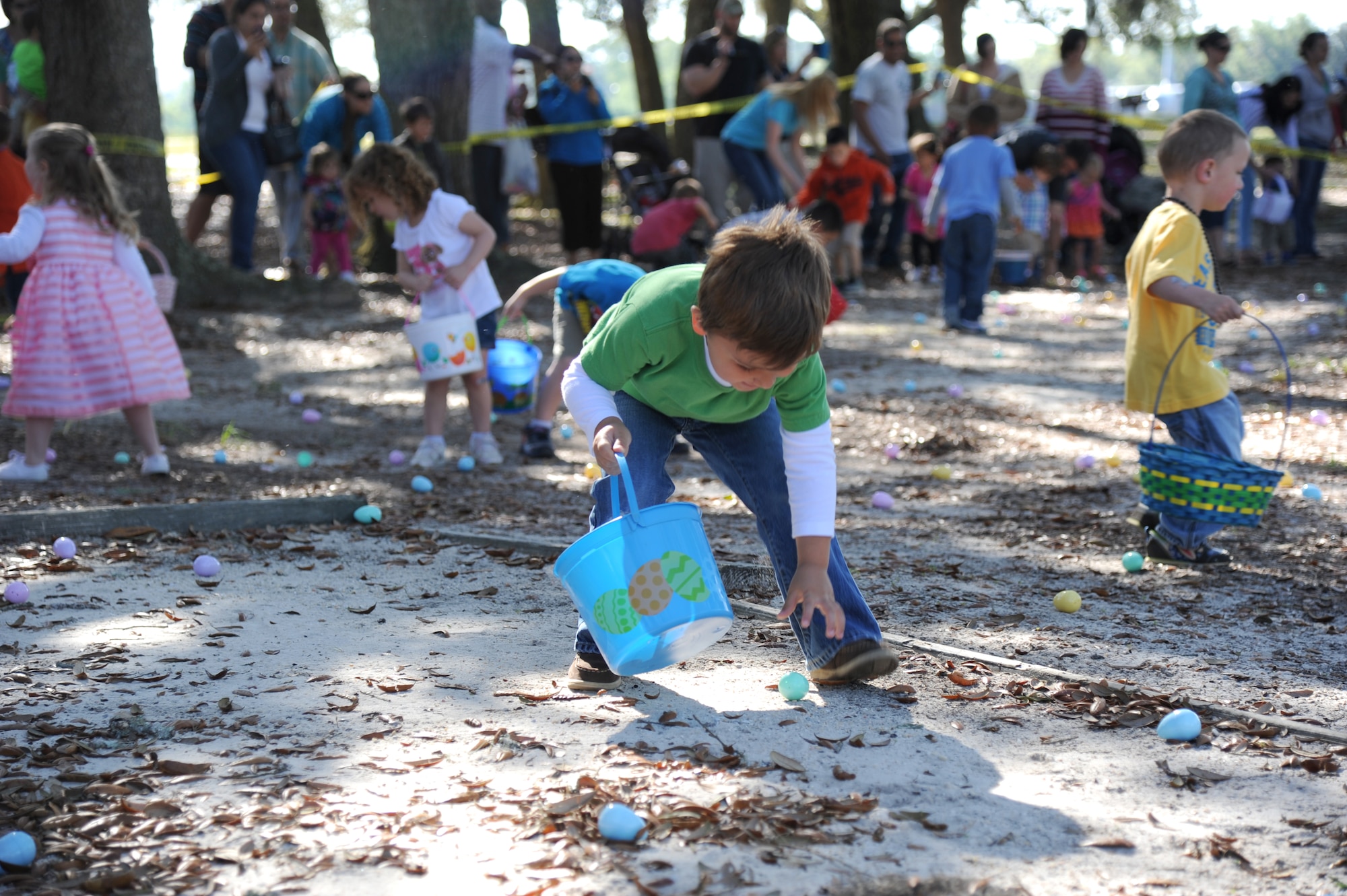 The grandson of retired Master Sgt. Robert Ellis reaches down to pick up a plastic egg during an Easter egg hunt April 19, 2014, at the marina, Keesler Air Force Base, Miss.  A parade through the marina preceded the hunt then the grand opening of the outdoor recreation’s splash pad immediately completed the festivities.  (U.S. Air Force photo by Kemberly Groue)