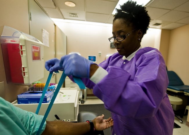 a woman wraps a band around a patient's arm in a lab