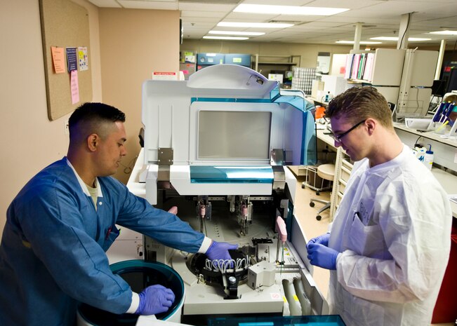Airman 1st Class Alex Gaheton (left), 99th Medical Support Squadron medical laboratory technician, and A1C Anthony Bush, 99th Medical Support Squadron medical laboratory technician student, conduct daily maintenance on a chemistry analyzer April 14, 2014, at Nellis Air Force Base, Nev. Medical laboratory technician students earn 53 Community College of the Air Force credits during their training. Nellis AFB has a 100 percent graduation rate and a 96 percent pass rate to become a nationally certified medical laboratory technician, which is the highest pass rate in the Air Force. (U.S. Air Force photo by Senior Airman Jason Couillard)