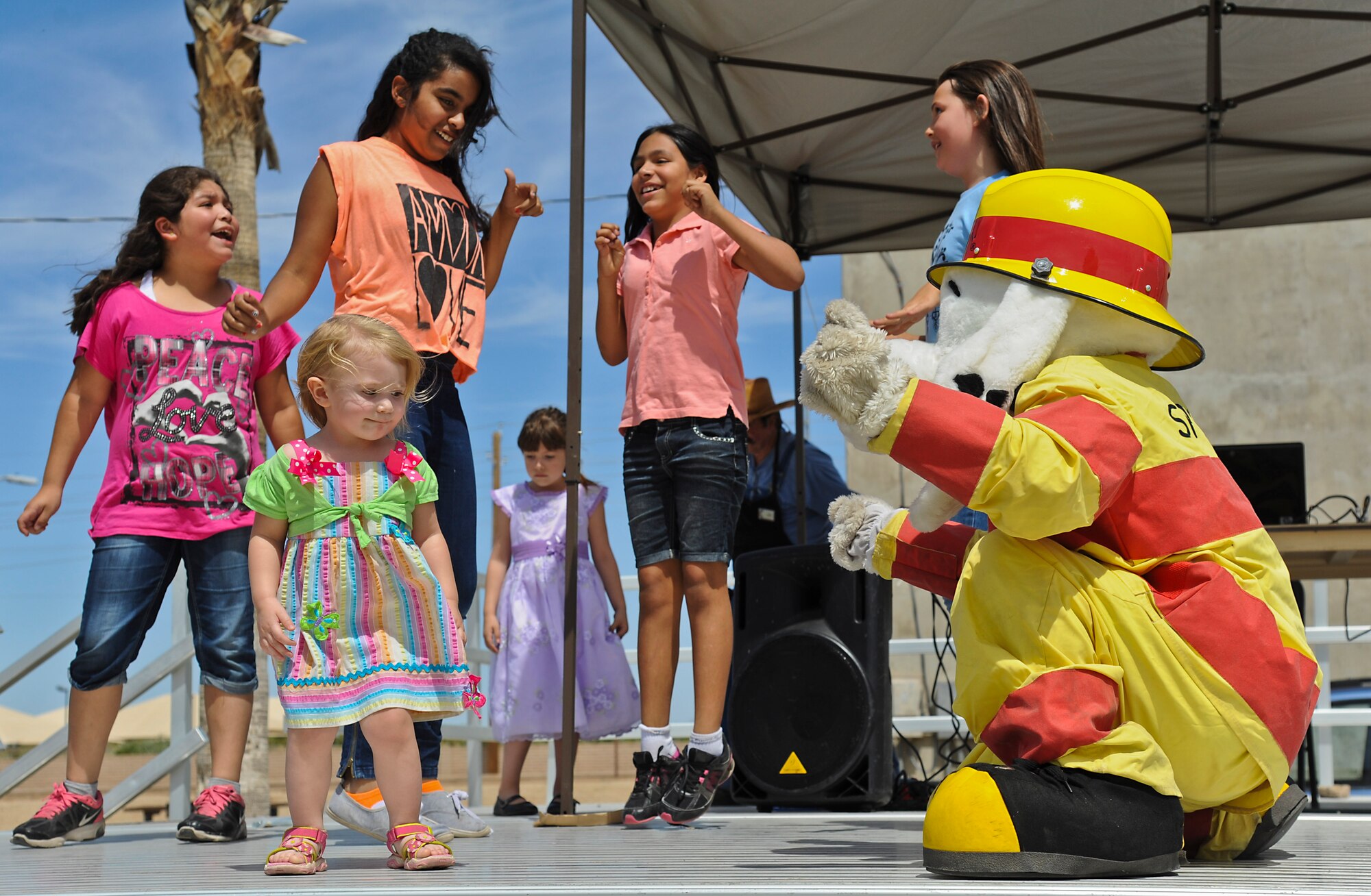 Sparky the Fire Dog busts a move with Ember Jackson, 2, daughter of Senior Airman Rachel Jackson, 62nd Aircraft Maintenance Unit weapons load crew member. (U.S. Air Force photo/Staff Sgt. Darlene Seltmann)