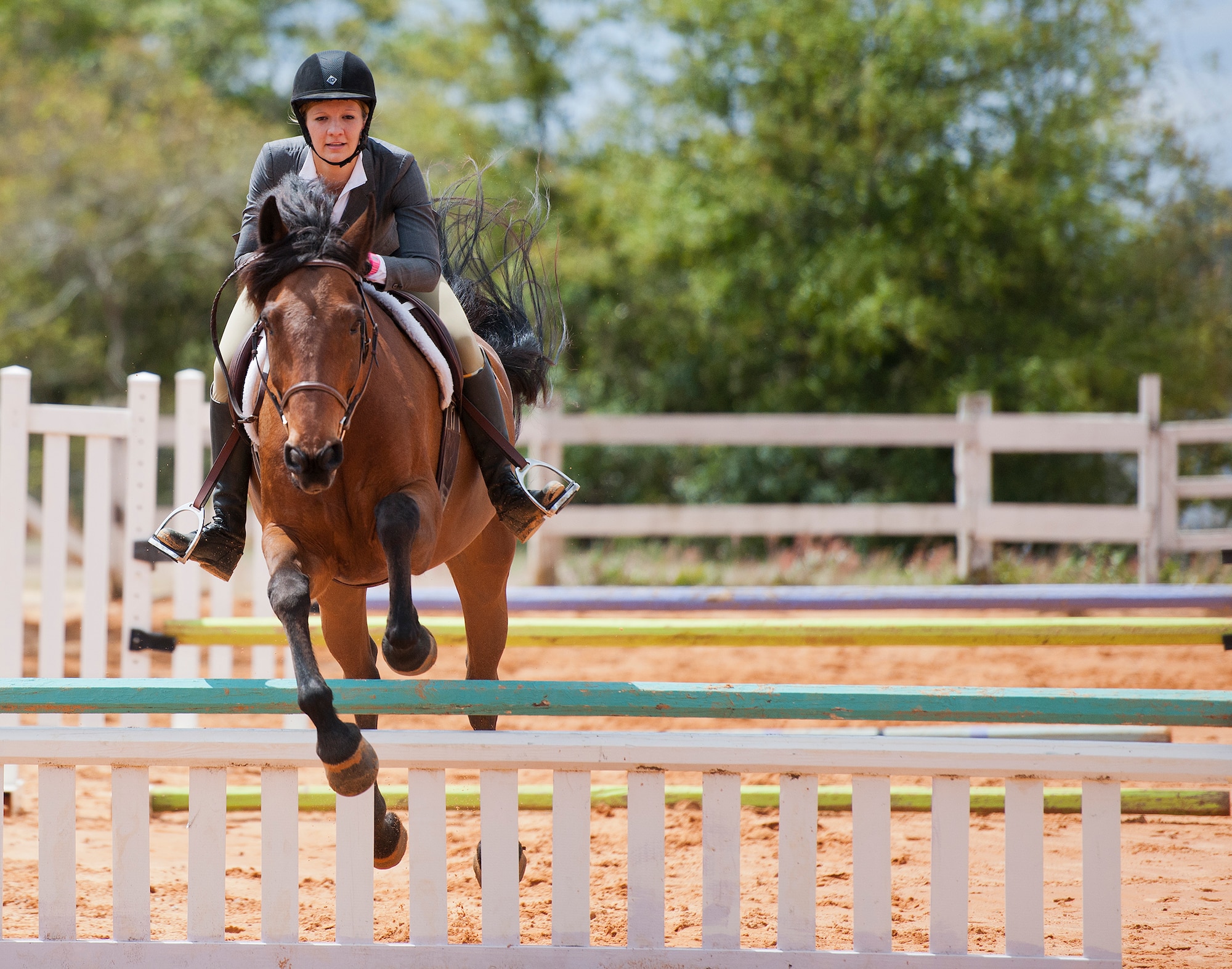 A rider and her horse jump over a barrier during a jumping demonstration at the Sand and Spur Riding Club open house event April 19 at Eglin Air Force Base, Fla.  The club provided pony rides for kids and riding and training demonstrations. Those who attended got an up close and hands-on experience with many of the different breeds of horses housed at the stables on base. (U.S. Air Force photo/Samuel King Jr.)