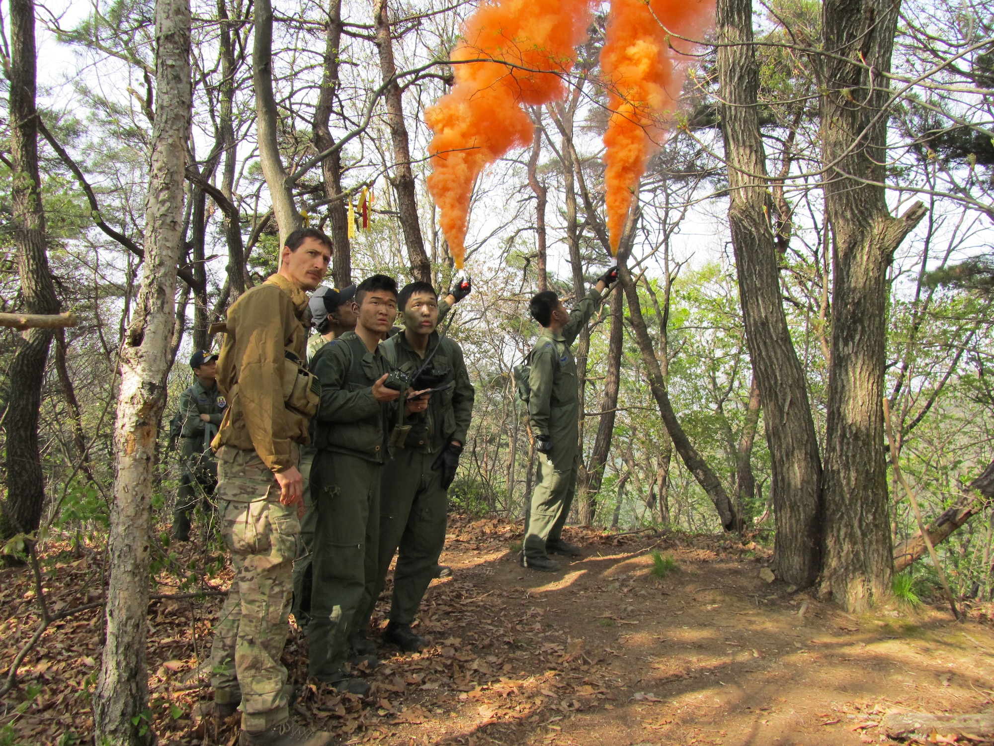 Students from the Republic of Korea Air Force Basic Mountain Survival Course show Tech. Sgt. Kurtis Douge, 8th Operations Support Squadron survival, evasion, resistance and escape specialist, signaling techniques during their course near Chong-Ju, ROK, April 11, 2014. The SERE specialist demonstrated survival techniques and evaluated and provided recommendations to improve the overall course taken by ROK survival students. (U.S. Air Force Courtesy Photo)