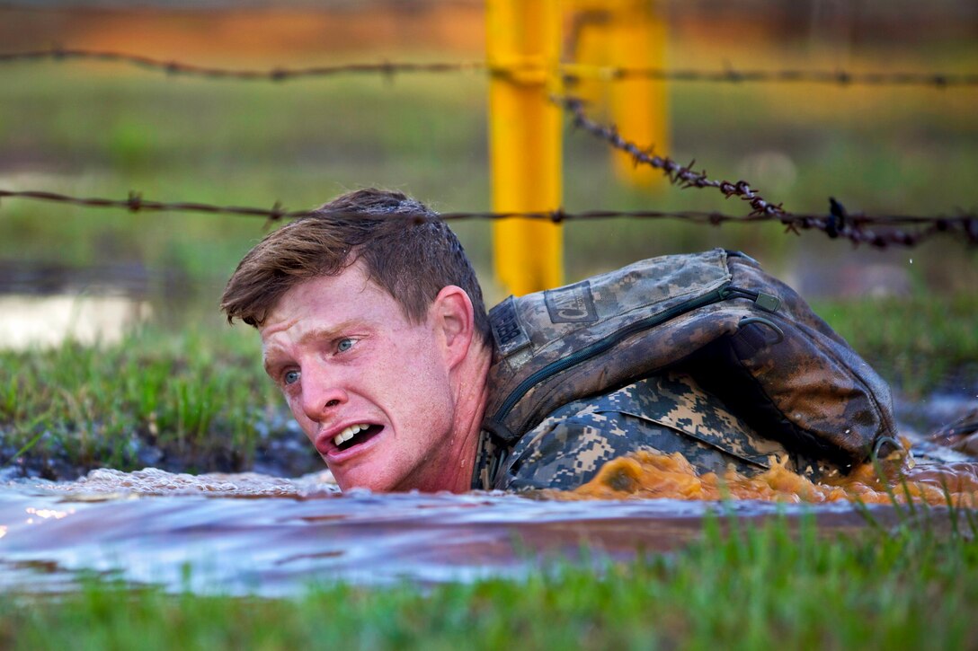 Army 2nd Lt. John Bergman crawls through a water obstacle on Fort Benning, Ga., April 11, 2014. Bergman is assigned to the 25th Infantry Division.