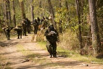 A squad leader with 2nd Maintenance Battalion, 2nd Marine Logistics Group leads his Marines through backwoods during a super squad competition aboard Camp Lejeune, N.C., April 17, 2014. Six squads competed against each other in multiple events that required land navigation and other military skills to be successful. (U.S. Marine Corps photo by Cpl. Shawn Valosin)