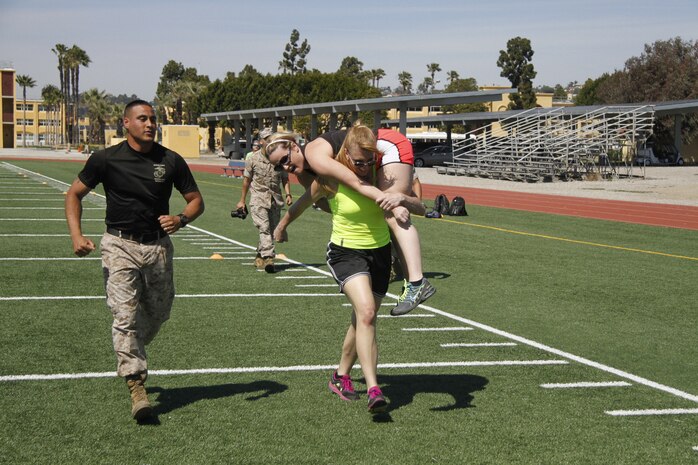 Liane R. Hager, a Harrisonville High School family and consumer sciences teacher, carries Jenny R. Bruns, a Harrisonville High School art teacher, as part of a mock Combat Fitness Test during the Educators' Workshop at Marine Corps Recruit Depot San Diego April 8, 2014. Educators from both Recruiting Station Kansas City and Lansing took part in the workshop. The workshop included the educators asking questions about the rigors of recruit training, firing the M16A4 assault rifle, amongst many other aspects of recruit training.